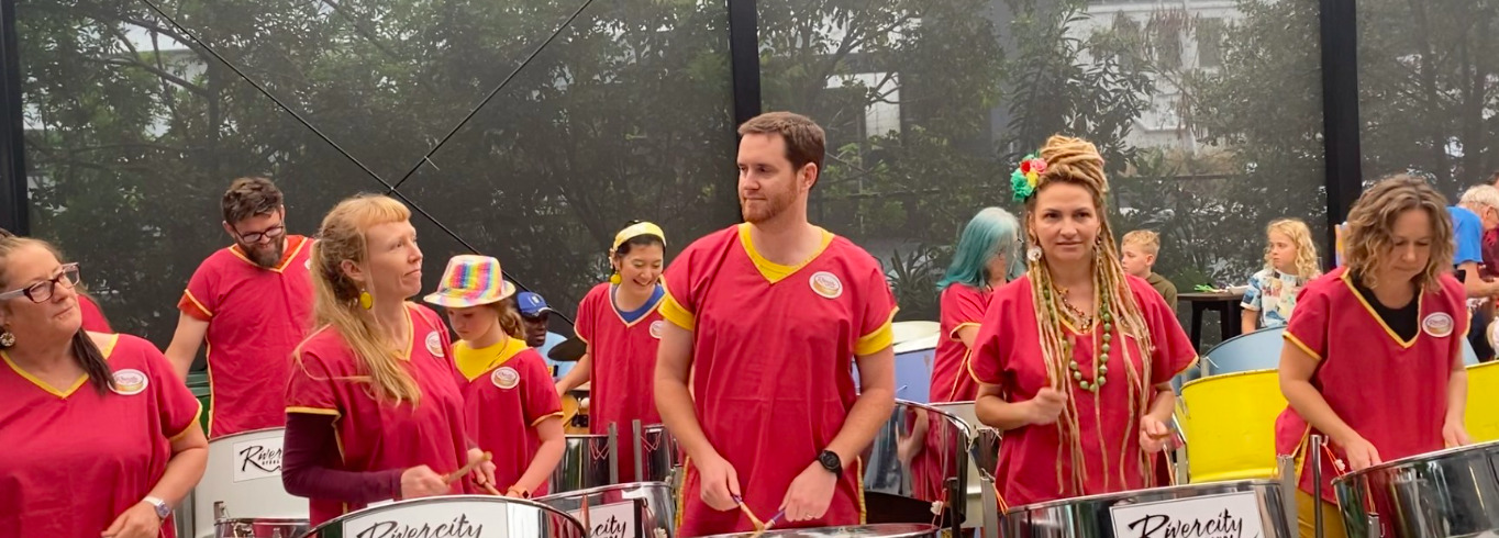 People dressed in Red outfits with big steel drums