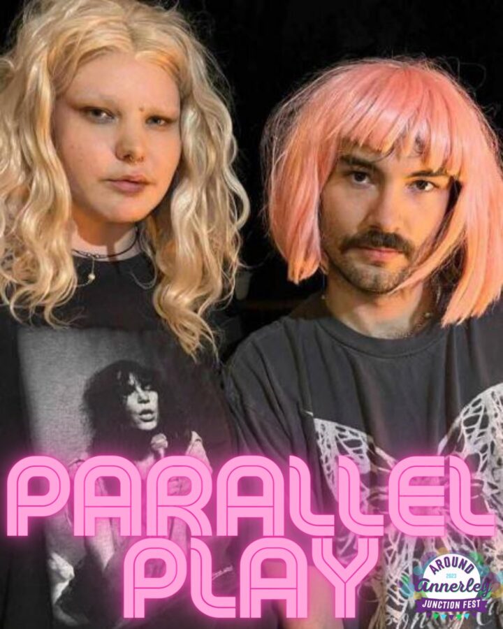 2 people, one is a boy with a moustache and a pink wig, the other is a girls with blonde hair
