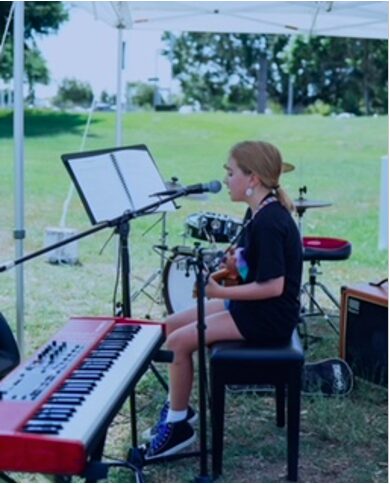 a girl sitting on a piano stool with a ukalele and a keyboard